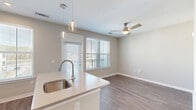 Located at 4600 Bakers Blessing Ln in Summerville, SC, this single-floor residence offers a thoughtfully designed layout that maximizes every square foot. The open-concept kitchen is a standout feature, boasting white shaker cabinetry, light quartz countertops, a center island with a stainless steel sink, and a full suite of stainless steel appliances including a refrigerator, range, and microwave. Pendant lighting above the island adds a modern touch, while recessed lighting ensures a bright, functional workspace. The kitchen flows seamlessly into the living and dining area, which benefits from natural light through large windows with views of the outdoors. A ceiling fan overhead enhances comfort in the living space. A stylish sliding barn door adds a contemporary architectural detail to the interior. The bedroom is a comfortable, carpet-floored retreat with a ceiling fan and access to a dedicated closet. The bathroom is clean and functional, featuring a white vanity with a framed mirror, a tub/shower combo with white tile surround, and wood-look flooring. Neutral warm-gray tones and wood-look flooring throughout the main living areas tie the space together with a cohesive, modern aesthetic.