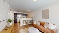 Located at 2281 E 89th St in Cleveland, OH, this efficient one-bedroom, one-bathroom unit offers a thoughtfully designed layout that maximizes every square foot. The open-concept living area is bathed in natural light from large windows fitted with blinds, creating a warm and inviting atmosphere. Hardwood-style flooring flows consistently throughout the space, lending a cohesive and modern feel.

The combined kitchen and dining area is a standout feature, anchored by a white breakfast bar with seating — perfect for casual dining. The kitchen is equipped with rich dark cabinetry, stainless steel appliances including a refrigerator, stove, microwave, and dishwasher, complemented by clean white countertops that provide ample prep space.

The bedroom is a comfortable retreat, featuring two windows with natural views, a ceiling fan, and access to two closets, offering generous storage. The full bathroom includes a dark vanity with white countertop, a tub-shower combination, and neutral tile flooring.

A hallway connects the main living areas to the private spaces, and the entry door includes a sidelight window that invites additional natural light. The overall design palette — neutral tones, clean lines, and modern finishes — creates a bright, functional, and welcoming living environment.