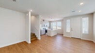 Located on Soapstone Street in Fort Worth, TX, this two-story home offers four bedrooms and four bathrooms across a well-designed layout. The main floor greets you with an open-concept living, dining, and kitchen area bathed in natural light from multiple windows dressed with clean white blinds. Warm wood-look flooring flows throughout, complemented by crisp white walls and recessed lighting. The kitchen is a standout feature, showcasing gray shaker cabinetry, white quartz countertops, a classic subway tile backsplash, stainless steel appliances, and a central island with an undermount sink and stylish pendant lighting. A ceiling fan adds comfort to the living area, while a staircase leads to the upper floor. Upstairs, four generously sized bedrooms each offer ceiling fans, wood-look flooring, and ample closet space, including walk-in closets with built-in shelving. The primary bedroom connects to its own private bathroom featuring a glass-enclosed walk-in shower with large-format tile. Additional full bathrooms serve the remaining bedrooms. A dedicated laundry area and an attached garage with interior access round out the functional layout of this move-in-ready home.