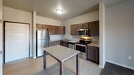 Located at 218 19th St SE in Watertown, South Dakota, this single-floor unit offers a practical and cohesive layout designed for comfortable everyday living. The kitchen serves as a functional centerpiece, outfitted with a full suite of stainless steel appliances including a refrigerator, electric range, over-the-range microwave, and dishwasher. Rich dark-toned cabinetry provides ample storage, while granite-look countertops extend across the workspace and onto a central island or peninsula, offering additional prep space and casual dining potential. Light vinyl plank flooring runs throughout the kitchen, lending a clean and durable surface underfoot. The kitchen flows seamlessly into an open living area, which features carpeted flooring and a sliding glass door that brings in natural light and provides outdoor access. A dedicated bedroom offers a quiet retreat with carpeted floors, a window with blinds that allows natural light and outdoor views, and baseboard heating. The bathroom is finished with matching dark cabinetry, a granite-look vanity countertop, an undermount sink, and light vinyl flooring, maintaining a consistent design palette throughout the unit. A textured ceiling treatment is present in the kitchen and living areas, adding a subtle architectural detail to the overall interior.