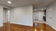 Located at 23 Wilfred St in West Orange, NJ, this single-floor unit offers a clean, modern aesthetic throughout. Rich, polished hardwood floors flow through the living areas and bedrooms, complemented by crisp white walls and recessed lighting that create a bright, welcoming atmosphere. The open layout connects the living space to the kitchen, which is outfitted with dark cabinetry, stainless steel appliances including a refrigerator, range, and microwave, and light wood-look tile flooring. A window allows natural light to filter in, adding to the functional yet stylish design. The bedrooms are well-proportioned, each featuring gleaming hardwood floors, recessed lighting, windows with outdoor views of surrounding greenery, and radiator heating units. The bathroom is tastefully renovated with a full soaking tub and shower combination, white subway tile surround, a white vanity with ample storage, brushed nickel fixtures, and wood-look tile flooring that ties the space together cohesively. Each room benefits from both a radiator heating system and wall-mounted air conditioning units, ensuring year-round comfort. The overall ambiance is clean, updated, and move-in ready.