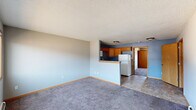 Located at 1241 Grand Ave in Marion, Iowa, this single-floor unit offers a practical and comfortable layout with a variety of functional spaces. The open living area is finished with plush gray carpet and light blue walls, creating a calm and inviting atmosphere. A textured ceiling adds character throughout the common areas. The kitchen is efficiently designed with warm oak cabinetry, dark granite-style countertops, tile flooring, and white appliances including a refrigerator, electric range, and over-the-range microwave. A pass-through counter connects the kitchen to the living area, enhancing the open feel of the space. The bedrooms are carpeted and feature neutral gray tones, with one room equipped with a ceiling fan and another offering a wood-trimmed window with views of the surrounding neighborhood. A walk-in closet with wire shelving provides ample storage. The bathroom features deep navy blue walls, a wood-vanity with a framed mirror, tile flooring, and a grab bar for added accessibility. Baseboard heating is present throughout, ensuring consistent warmth. The entry area transitions smoothly from tile to carpet, offering a welcoming introduction to the unit.