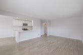 Located at 23500 Anza Ave in Torrance, CA, this single-floor residence offers a thoughtfully updated interior with a clean, modern aesthetic throughout. The open-concept kitchen is a standout feature, equipped with white shaker-style cabinetry extending to the ceiling, striking quartz countertops with subtle veining, and a full suite of stainless steel appliances including a gas range, over-the-range microwave, and a side-by-side refrigerator with ice and water dispenser. A peninsula with an integrated sink adds additional prep space and creates a natural transition into the living area. Light wood-tone flooring runs consistently throughout the unit, lending warmth and visual continuity across all rooms. The living and dining areas are open and airy, benefiting from natural light through horizontal-slatted blinds and direct access to an outdoor area via a front-facing door. The bedrooms are well-proportioned, each featuring ceiling fans, windows with outdoor greenery views, and ample closet space — including mirrored sliding-door closets. The bathroom is functional and clean, featuring a full soaking tub and shower combination with built-in corner shelving and a chrome grab bar. Neutral wall tones and recessed lighting complete the fresh, move-in-ready feel of this Torrance residence.