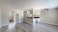 Located in Torrance, CA, this 1-bedroom, 1-bathroom unit offers a clean, modern aesthetic with consistent light wood-style flooring and a neutral gray-and-white color palette throughout. The open-concept living and kitchen area forms the heart of the home, where a half-wall partition defines the kitchen space while maintaining an airy, connected feel. The kitchen is well-appointed with white shaker cabinetry, dark countertops, stainless steel appliances including a gas range and refrigerator, and a stainless steel island hood, making it both functional and visually striking. A single-basin sink with ample counter space completes the galley-style layout. The living area is bright, with natural light flowing in through blinds-covered windows and access to the unit's entry door. The spacious bedroom offers a comfortable retreat, featuring a wide window for natural light and a full-width mirrored sliding closet that adds depth and storage. The bathroom is efficiently designed with white cabinetry, dark countertops, and a glass-enclosed shower and tub combination with sleek chrome fixtures. A hallway connects the main living spaces, completing this well-organized and move-in-ready home.