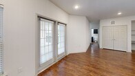 Located in Austin, TX, this 2-bedroom, 2-bathroom single-floor residence offers a well-designed layout with a clean, modern aesthetic throughout. The open-concept kitchen and living area serves as the heart of the home, featuring rich wood-style flooring, dark espresso cabinetry, granite countertops, and a large central island with pendant lighting overhead — ideal for both everyday living and entertaining. Black appliances complement the kitchen's bold color palette.

A bright hallway with large windows connects the living space to the private quarters, allowing natural light to flow through the unit. The primary bedroom features wood-style flooring, a window with exterior views, and access to a generously sized walk-in closet outfitted with dual hanging rods and built-in shelving for ample storage. The second bedroom is carpeted and includes a window with a view of the surrounding neighborhood.

Both bathrooms maintain a consistent design with dark vanity cabinetry, granite countertops, and wood-style flooring. The primary bath includes a walk-in shower with a glass sliding door and grab bars, while the secondary bath features a shower-tub combination. Additional conveniences include a dedicated laundry area and multiple closets throughout. The space presents a functional, well-appointed layout suited for comfortable everyday living.