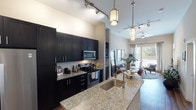 Located at 351 E Dry Creek Rd in Littleton, Colorado, this thoughtfully designed single-floor residence blends modern aesthetics with functional living. The open-concept kitchen serves as the heart of the home, showcasing dark espresso cabinetry that extends floor to ceiling, striking granite countertops, and a spacious island with an undermount sink. Stainless steel appliances — including a side-by-side refrigerator, electric range, and built-in microwave — complete the sleek culinary space. Stylish pendant lighting and a track lighting system illuminate the kitchen and flow seamlessly into the adjacent living and dining areas. The living room is warm and inviting, featuring hardwood-style flooring, large sliding glass doors that flood the space with natural light, and views of the outdoors. The bedroom offers a tranquil retreat with plush carpeting, a window with outdoor views, and direct access to an en-suite bathroom. The bathroom is appointed with granite countertops, a dark-framed vanity mirror, and a tiled tub-shower combination, maintaining the home's cohesive modern design language throughout. Neutral tones and clean lines unify each space, creating a contemporary and comfortable living environment.