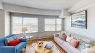 This single-floor residence offers a thoughtfully designed layout that balances comfort and functionality throughout. The living room serves as a bright, welcoming centerpiece, featuring warm hardwood-style flooring, a textured ceiling, and a generous bank of windows fitted with horizontal blinds that frame expansive outdoor views and flood the room with natural light. A dedicated nook adjacent to the living area provides an ideal workspace, complete with its own window overlooking the surroundings.

The kitchen is both stylish and practical, showcasing dark espresso cabinetry, stainless steel appliances including a refrigerator and range, and a granite-topped breakfast bar that seamlessly connects to the dining area. The open-concept flow between the kitchen and dining space encourages easy entertaining and everyday living.

The bedroom is a calm retreat, finished with plush carpeting and a textured ceiling. A large window allows natural light to fill the room while offering views of the outdoors, creating a serene atmosphere. The room provides ample space for furnishings and relaxation.

The bathroom features a granite-topped vanity with dark wood cabinetry, an undermount sink, and a well-lit mirror, maintaining the consistent quality and finish found throughout the home. Hardwood-style flooring extends into this space, tying the overall aesthetic together cohesively.