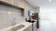 Located at 5401 Atlantic Springs Rd in Raleigh, NC, this single-floor residence offers a thoughtfully designed interior defined by clean lines and modern finishes throughout. Light wood-look plank flooring runs consistently across the living areas, bedrooms, and utility spaces, creating a cohesive and bright aesthetic.

The kitchen is a standout feature, equipped with stainless steel appliances including a range, over-the-range microwave, and refrigerator with ice and water dispenser. Warm-toned wood cabinetry extends to the upper and lower levels, complemented by white quartz-style countertops and a subway tile backsplash in soft gray tones. A stainless steel undermount sink with a modern gooseneck faucet adds a refined touch.

The living and bedroom areas are bright and open, with large windows allowing generous natural light to fill each room. Neutral-toned walls provide a versatile backdrop, and a ceiling fan is featured in one of the bedrooms.

The bathroom is well-appointed with a glass-enclosed walk-in shower tiled in classic white subway tile, a wood-toned vanity with a white countertop, and wood-look flooring. A dedicated laundry area houses a stacked washer and dryer unit alongside built-in shelving, providing practical in-unit convenience.