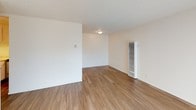 This single-floor 1-bedroom, 1-bathroom unit offers a practical and comfortable layout designed to maximize livable space. The living area is bright and open, featuring warm wood-style laminate flooring that extends throughout the unit. A large sliding glass door fitted with vertical blinds floods the room with natural light while providing outdoor access. A textured ceiling adds dimension overhead, and a wall-mounted heater unit ensures year-round comfort.

The kitchen is efficiently designed and equipped with white cabinetry offering ample storage above and below the countertops. A stainless steel sink sits alongside light-toned countertops, while a black and stainless steel electric range with a built-in overhead exhaust hood serves as the focal point of the cooking space.

The bathroom features a white vanity with a single sink, light countertops, and a mirrored medicine cabinet with integrated lighting above. A full-size soaking tub with a shower fixture is situated adjacent to the vanity, complemented by wood-style flooring that ties the space together with the rest of the unit. The overall aesthetic is clean, neutral, and move-in ready.