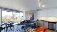 Located at 1101 East Bayaud Avenue in Denver, CO, this modern single-floor residence offers a thoughtfully designed open-concept layout that blends style and functionality. The living area is bright and inviting, anchored by floor-to-ceiling windows that flood the space with natural light and frame picturesque views of the surrounding Denver cityscape and lush tree canopy. The living room features contemporary furnishings, track lighting, and a bold abstract canvas that adds a vibrant focal point to the neutral palette. Seamlessly connected to the living area, the kitchen is outfitted with sleek cabinetry in a clean white and warm wood finish, dark countertops, and modern fixtures — striking a balance between aesthetic appeal and practicality. The overall design embraces a clean, contemporary aesthetic with smooth white ceilings, cool grey tones, and carefully curated accents that create a cohesive and sophisticated ambiance throughout. Situated in Denver's desirable Washington Park neighborhood, residents enjoy close proximity to parks, dining, and urban amenities, making this a well-positioned space in one of the city's most sought-after communities.