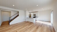 This well-designed 3-floor home offers a clean, contemporary aesthetic carried throughout each level. The main living area is anchored by an open-concept layout where a spacious living room flows seamlessly into the kitchen, creating an inviting and functional space ideal for everyday living and entertaining. Light hardwood flooring extends across the main level, complementing the bright, neutral palette of white walls and recessed lighting.

The kitchen is a standout feature, outfitted with crisp white shaker-style cabinetry, granite countertops, and a full suite of stainless steel appliances including a gas range, built-in microwave, and a French door refrigerator. A central island with a sink and pendant lighting above adds both workspace and a casual gathering spot. A sliding door provides access to an outdoor area, filling the kitchen with natural light.

A conveniently located half bath is accessible near the staircase on the main level. Upper-level bedrooms are generously sized and carpeted, offering a comfortable retreat, with a full bathroom featuring granite countertops, a single vanity, and a tub-shower combination. The lower level provides additional carpeted rooms, suitable for flexible use, along with recessed lighting and ample wall outlets throughout.