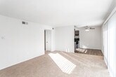 This single-floor unit offers a well-organized layout with clearly defined living, sleeping, and functional spaces. The living area is generously sized, featuring warm neutral carpet and an abundance of natural light streaming through large sliding glass doors that open to an outdoor patio. Vertical blinds provide privacy while maintaining access to outdoor views. The space connects openly to the kitchen area, which is equipped with dark espresso-toned cabinetry, a mosaic tile backsplash, dark countertops, a built-in sink, and a black gas range with overhead ventilation. The wood-look flooring in the kitchen adds a practical contrast to the carpeted living spaces.

Two bedrooms are located off the main living area, each finished with plush carpet, neutral walls, and individual windows that bring in natural light. Both bedrooms include dedicated closets with built-in rods and shelving, offering practical storage. The bathroom features wood-look vinyl flooring, a full-size soaking tub with a shower and curved curtain rod, and a vanity with a light countertop. The overall ambiance of the unit is clean, bright, and functional, with a cohesive neutral palette throughout.