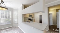 Located at 2500 Grove Club Lane in Cary, NC, this single-floor residence offers a thoughtfully designed layout with a clean, neutral aesthetic throughout. The open living area is finished with durable wood-look flooring, crown molding, a ceiling fan, and built-in shelving that adds both character and functional storage. Sliding glass doors lead directly to a private balcony, flooding the space with natural light and providing outdoor views of the surrounding greenery.

The kitchen is outfitted with light wood cabinetry, ample counter space, a stainless steel sink, and a full suite of appliances including an electric range with overhead microwave. Wood-look flooring continues through the kitchen, reinforcing the cohesive design of the home.

Bedrooms feature plush carpeting, ceiling fans, and windows with views of the landscaped exterior, creating a comfortable and restful atmosphere. Closets provide generous wire-rack shelving for organized storage.

The bathroom is a standout feature, presenting a long dual-sink vanity with white countertops, a large wall mirror, wood-look flooring, and a tiled tub-shower combination equipped with accessibility grab bars. A built-in linen closet adds further convenience.

A dedicated in-unit laundry area accommodates a full-sized washer and dryer, completing the practical and well-appointed nature of this Cary residence.