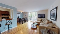 This single-floor residence offers a thoughtfully designed layout that seamlessly connects the main living areas. The living room is bright and inviting, featuring warm hardwood flooring, a large sliding glass door that floods the space with natural light, and direct access to a private outdoor balcony with greenery views. The open flow leads into the dining area, distinguished by a cool blue accent wall, a ceiling fan, and a sliding door that also opens to the balcony, creating a comfortable and airy atmosphere ideal for everyday meals or entertaining.

The kitchen is well-equipped, showcasing rich dark wood cabinetry, granite countertops with warm golden tones, a tile backsplash, and tile flooring — providing both style and practicality for cooking and meal preparation.

The bedroom is a peaceful retreat with soft neutral tones, plush wall-to-wall carpeting, and wall-mounted lighting that adds a modern touch. The bathroom features tile flooring in a classic diamond pattern, a full soaking tub with shower, and clean white finishes throughout.

Overall, the space combines functional design with comfortable living, highlighted by consistent hardwood flooring in the common areas, an abundance of natural light, and a cohesive neutral color palette accented with warm wood tones.