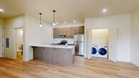 Located in Vancouver, WA, this single-floor residence offers three bedrooms and two full bathrooms with a thoughtfully designed open-concept layout. The kitchen and living room share a bright, cohesive space anchored by a large island with a white quartz countertop, double undermount sink, and modern pendant lighting. Warm-toned cabinetry pairs with stainless steel appliances — including a refrigerator, range, and microwave — creating a functional and contemporary kitchen. Light wood vinyl plank flooring runs throughout the entire residence, contributing to a clean, unified aesthetic. The living area benefits from generous natural light through large windows and offers direct access to an outdoor area through a glass door. A dedicated in-unit laundry area with a full-size washer and dryer provides added convenience. The primary bedroom is a well-proportioned retreat featuring a wall-mounted mini-split HVAC unit, a wide window for natural light, and a closet with bi-fold doors. Additional bedrooms are bright and versatile, each with light-filled windows and neutral walls. Both bathrooms feature wood-toned vanities with white countertops, tub/shower combinations, and light wood flooring. A dedicated closet completes the layout, offering practical storage throughout.