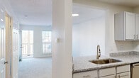 Located at 2400 Cluette Dr in Raleigh, NC, this one-bedroom, one-bathroom residence offers a well-designed single-floor layout that maximizes every square foot. The open-concept kitchen and living area form the heart of the home, where the kitchen impresses with granite countertops, gray cabinetry, a stainless steel sink with a modern pull-down faucet, and a full suite of stainless steel appliances, including a refrigerator and range. Light wood-look flooring runs throughout the kitchen, complementing the bright, neutral palette. A structural column elegantly separates the kitchen from the living area, which features plush carpeting, a large window overlooking a balcony, and access to the outdoors — filling the space with natural light. The spacious bedroom is carpeted and includes a ceiling fan with light fixture, a generously sized window, and two closets providing ample storage. A hallway connects the main living areas to the full bathroom, which is outfitted with a soaking tub and shower combination, brushed nickel hardware, and light wood-look flooring. Clean white walls and textured ceilings throughout the residence create a bright, neutral canvas ready for personalization.