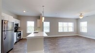 This single-floor residence offers a thoughtfully designed open-concept layout that seamlessly connects the kitchen and living area. The kitchen is outfitted with white shaker-style cabinetry, quartz countertops, a dark subway tile backsplash, stainless steel appliances, and a peninsula with an integrated sink and pendant lighting overhead. The adjoining living area is generously proportioned, featuring warm wood-look flooring, a ceiling fan, and multiple windows that invite abundant natural light and outdoor views.

A hallway with a louvered utility closet leads to the private quarters of the home. The bedrooms are carpeted for comfort and each feature ceiling fans and windows with views of the surrounding landscape. The primary bedroom includes a walk-in closet equipped with wire shelving and rack systems, providing ample storage.

Both bathrooms are finished consistently, each offering a quartz-topped vanity with white cabinetry, tile flooring, and a full tub-shower combination with floor-to-ceiling tile surround and a curved curtain rod. The neutral warm-gray color palette carried throughout the home creates a cohesive and calming ambiance. Clean lines, consistent finishes, and an abundance of natural light define the overall character of this well-appointed residence.