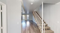 Located at 2001 S Haster St in Anaheim, California, this two-story residence offers a clean, modern aesthetic throughout its well-maintained interior. The main level welcomes you with durable wood-look flooring that flows seamlessly through the open living areas, complemented by soft gray walls and crisp white trim. A carpeted staircase with a white railing connects the two floors, adding a classic touch to the layout. The living area is bright and open, with sliding glass doors and vertical blinds that lead to a private outdoor patio, allowing natural light to fill the space. The kitchen features white cabinetry with ample storage, granite-patterned countertops, and a white appliance suite, creating a functional and cohesive cooking environment. The upper level hosts well-proportioned bedrooms, including one with a mirrored sliding-door closet and an electrical panel for added utility. Additional bedrooms are bright, with windows fitted with vertical blinds offering outdoor views. The bathrooms are finished with granite-topped vanities, mirrors, and wood-look flooring that maintains consistency with the rest of the home. Crown molding accents select areas, adding architectural detail throughout. The overall ambiance is light, neutral, and move-in ready.