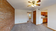 This single-floor unit is defined by its standout exposed brick accent walls, which appear prominently in the living area and extend toward the entry, lending an industrial-meets-residential character to the space. The living area is carpeted and fitted with a ceiling fan with light kit, providing both comfort and airflow. A front entry door opens directly into this main space, which connects openly to the rest of the unit.

The kitchen features warm honey-toned wood cabinetry with ample upper and lower storage, a double-basin sink, a dishwasher, and a full-size refrigerator. The kitchen and dining area are finished with wood-look vinyl plank flooring, and a window allows natural light into the dining space.

The bedrooms are carpeted and each includes closet space with wire shelving for organized storage. One bedroom also features an exposed brick wall and a window bringing in natural light. Interior doors throughout are finished in warm wood tones consistent with the cabinetry.

The bathroom is cleanly appointed with a wood-vanity with countertop storage, a tub-shower combination, and wood-look vinyl plank flooring, maintaining a cohesive aesthetic across the unit.