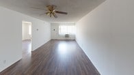 Located at 720 W 27th St in Los Angeles, CA, this single-floor unit offers a practical and well-organized layout with a clean, neutral aesthetic throughout. The open living area is a standout feature, showcasing rich, dark hardwood-style flooring that contrasts beautifully with the bright white walls and textured ceiling. A ceiling fan with integrated lighting provides both comfort and illumination, while a window with vertical blinds allows natural light to fill the space. An in-wall air conditioning unit ensures year-round climate control.

The kitchen is efficiently designed in a galley-style configuration, featuring dark grey cabinetry with modern hardware, brown laminate countertops, a stainless steel sink, a white refrigerator, and a range. Light tile flooring keeps the space bright and easy to maintain.

The bedrooms continue the dark hardwood-style flooring and feature large windows with vertical blinds, offering ample natural light and views of the surrounding neighborhood. The textured ceilings are consistent throughout.

Two bathrooms serve the unit. The first includes a tub and shower combination with sliding frosted glass doors, a toilet, a window for natural ventilation, and a vanity. The second bathroom features a vanity with a large mirror, a countertop sink, and a separate shower area. Both bathrooms are finished with light tile flooring and neutral tones.