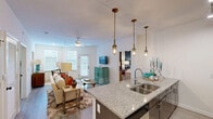 Located at Marina Village Drive in Mount Holly, NC, this single-story residence offers two bedrooms and two bathrooms within a thoughtfully designed floor plan. The open-concept kitchen and living area serves as the heart of the home, where the kitchen features dark cabinetry, stainless steel appliances, a white subway tile backsplash, and granite countertops extending across a breakfast bar illuminated by industrial-style gold pendant lights. The living room connects seamlessly, benefiting from natural light through multiple windows and a sliding door, with light wood-style flooring and a ceiling fan overhead.

The primary bedroom is a well-sized retreat highlighted by a bold navy accent wall, carpet flooring, and access to a walk-in closet equipped with wire shelving. Its en-suite bathroom includes a glass-enclosed walk-in shower with built-in shelving. The second bedroom features carpet, a ceiling fan, a window for natural light, and a dedicated closet. The second bathroom offers a full tub-shower combination, granite vanity, and wood-style tile flooring. A dedicated laundry area adds everyday convenience, completing this functional and stylish residence.