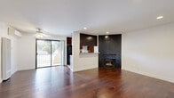 This thoughtfully designed 1-bedroom, 1-bathroom residence offers a comfortable and cohesive living experience across a single floor. Rich, warm-toned hardwood flooring flows consistently throughout the main living areas and bedroom, lending the space a unified and inviting character.

The living room serves as the centerpiece of the home, highlighted by a striking corner fireplace clad in dark chevron-patterned tile — a bold architectural focal point. Recessed lighting and a ceiling fan add both functionality and ambiance, while a sliding glass door opens to a private balcony with outdoor views, allowing natural light to fill the space.

The kitchen features rich dark wood cabinetry reaching toward the ceiling, granite-style countertops, tile flooring, and a pass-through counter that connects it to the living area. Appliances include a full-size refrigerator and a gas range.

The spacious primary bedroom includes recessed lighting, hardwood floors, a window with outdoor views, and direct access to a dedicated closet. Two closets total provide ample storage throughout the unit.

The bathroom is well-equipped with a granite-topped vanity, white cabinetry, a framed mirror, tile flooring, and a full shower-tub combination. A hallway connects the rooms, completing this efficiently laid-out and move-in-ready home.