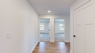 Located at 555 Court St in Auburn, Maine, this thoughtfully designed single-floor unit offers a clean, modern aesthetic throughout. The open living area is bathed in natural light from large double-hung windows and features light-toned hardwood-style flooring that extends seamlessly through the main living spaces, creating a warm and cohesive feel.

The kitchen is a standout feature, equipped with white shaker-style cabinetry, light granite countertops, and a full suite of stainless steel appliances including a refrigerator, electric range, and over-the-range microwave. A peninsula with an integrated sink provides additional prep space and serves as a natural divide between the kitchen and living area.

The bedrooms are carpeted for comfort and each receives generous natural light through individual windows that frame views of the surrounding New England landscape. Black hardware accents on doors and fixtures add a contemporary touch throughout.

A full bathroom includes a soaking tub with a shower curtain rod and hardwood-style flooring. The dedicated in-unit laundry area is equipped with a full-size top-loading washer and dryer with overhead wire shelving for additional storage. The living space also features a wall-mounted mini-split unit and a door leading to an outdoor balcony, extending the living experience beyond the interior.