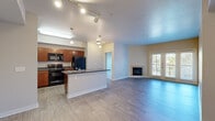 Located at 588 N Lincoln Ave in Loveland, Colorado, this 2-bedroom, 2-bathroom residence offers a well-designed single-level layout with a comfortable and functional flow. The open-concept living and kitchen area serves as the heart of the home, where wood-style plank flooring extends throughout and track lighting illuminates the space. The kitchen features rich medium-toned cabinetry, dark countertops, a suite of black appliances including a refrigerator, range, and microwave, and a peninsula with a double sink that provides additional prep and seating space. The living room is bright and airy, anchored by a tile-surround fireplace and French doors that open to a private balcony with outdoor views, allowing natural light to pour in. Both bedrooms are carpeted and outfitted with ceiling fans, offering a quiet and comfortable retreat. The primary bedroom is generously sized and connects to a full bathroom featuring dual sinks with warm-toned countertops, a soaking tub, and direct access to a walk-in closet with wire shelving. A second closet provides additional storage. The overall ambiance is clean, neutral, and move-in ready, making this Loveland residence a practical and inviting place to call home.