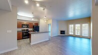 Located at 588 N Lincoln Ave in Loveland, Colorado, this 2-bedroom, 2-bathroom residence offers a well-designed single-level layout with a comfortable and functional flow. The open-concept living and kitchen area serves as the heart of the home, where wood-style plank flooring extends throughout and track lighting illuminates the space. The kitchen features rich medium-toned cabinetry, dark countertops, a suite of black appliances including a refrigerator, range, and microwave, and a peninsula with a double sink that provides additional prep and seating space. The living room is bright and airy, anchored by a tile-surround fireplace and French doors that open to a private balcony with outdoor views, allowing natural light to pour in. Both bedrooms are carpeted and outfitted with ceiling fans, offering a quiet and comfortable retreat. The primary bedroom is generously sized and connects to a full bathroom featuring dual sinks with warm-toned countertops, a soaking tub, and direct access to a walk-in closet with wire shelving. A second closet provides additional storage. The overall ambiance is clean, neutral, and move-in ready, making this Loveland residence a practical and inviting place to call home.