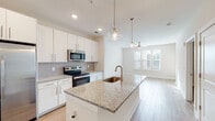 Located at 1749 Sea Pine Blvd in Myrtle Beach, SC, this single-floor residence offers a clean, contemporary design with a bright and airy aesthetic throughout. The open-concept kitchen serves as the heart of the home, showcasing a large central island topped with speckled granite countertops and an undermount sink, complemented by stylish pendant lighting. White shaker-style cabinetry extends to the ceiling, providing generous storage, while stainless steel appliances — including a side-by-side refrigerator with ice dispenser, electric range, microwave, and dishwasher — complete the sleek look. A subway tile backsplash adds a refined touch. Light hardwood-style flooring flows seamlessly from the kitchen into the open living and dining areas, which are filled with natural light from multiple windows dressed with horizontal blinds. The bedroom features plush carpeting, a ceiling fan with integrated lighting, and a natural light source from a well-positioned window. The en-suite bathroom is appointed with granite countertops, white cabinetry, a glass-enclosed shower, and hardwood-style flooring. A spacious walk-in closet with wire shelving rounds out the private quarters, offering ample organizational space. The overall ambiance is fresh, modern, and move-in ready.