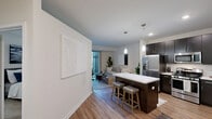 Located at 2550 Waterview Dr in Northbrook, IL, this one-bedroom, one-bathroom residence offers a thoughtfully designed layout across a single floor. The open-concept kitchen is a standout feature, showcasing rich dark cabinetry, stainless steel appliances including a gas range, microwave, and French door refrigerator, along with a crisp white quartz island with bar seating and elegant pendant lighting overhead. Wood-look flooring flows throughout the main living areas, adding warmth and cohesion to the space. The living room is bright and welcoming, highlighted by large sliding glass doors that open to an outdoor patio area, filling the room with natural light and providing a seamless connection to the outdoors. The bedroom features plush carpeting, a window for natural light, and a built-in closet with organized shelving, offering ample storage. The bathroom is finished with dark cabinetry, a white quartz vanity, wood-look flooring, and a full tub-shower combination. Clean white walls and modern finishes throughout lend the space a contemporary, move-in-ready feel. A dedicated closet provides additional storage, completing this efficiently designed residence.