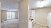 Located at 430 Lash Dr in Salisbury, NC, this single-floor unit offers a practical and well-organized layout comprising one bedroom, one bathroom, and a combined kitchen and living area. Warm neutral tones and clean white trim carry throughout the space, lending a consistent and understated aesthetic.

The living area features wall-to-wall carpeting, a ceiling fan with light fixture, and a textured ceiling. Large windows allow natural light to filter in, with sliding glass doors providing additional brightness and outdoor views. A built-in wall HVAC unit offers convenient climate control.

The galley-style kitchen is efficiently arranged with white cabinetry lining both sides, a stainless steel sink, light-toned countertops, tile flooring in a stone pattern, and white appliances including a refrigerator and electric range. Overhead fluorescent lighting keeps the kitchen well-lit.

The generously sized primary bedroom continues the carpeted flooring and neutral palette, with a ceiling fan, natural light from a window, and ample wall space. An adjacent vanity area with a built-in cabinet and mirror provides additional utility.

The bathroom includes a full tub/shower combination with accessibility grab bars installed on the walls and along the tub, complemented by wood-look flooring. Throughout the unit, the design prioritizes functionality, clean finishes, and a comfortable, move-in-ready environment.