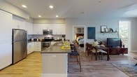 Located in the Northridge neighborhood of Los Angeles, this well-appointed single-story residence offers a thoughtfully designed open-concept layout with modern finishes throughout. The kitchen serves as the heart of the home, featuring white shaker-style cabinetry, dark countertops, stainless steel appliances including a refrigerator, microwave, and range, and a central island with bar seating — ideal for both cooking and casual dining. The kitchen flows seamlessly into a dedicated dining area and an adjacent living room, which is outfitted with wood-look flooring, a ceiling fan, and generous natural light. The bedrooms are carpeted for comfort and feature large windows with blinds that invite ample natural light. The primary bedroom includes access to a walk-in closet and an en-suite bathroom with a dual-sink vanity, dark countertops, white cabinetry, and a soaking tub. A second bathroom mirrors the clean, contemporary aesthetic with a single vanity, large mirror, and tile flooring. Throughout the residence, a neutral color palette of soft grays and whites creates a cohesive, modern ambiance, complemented by consistent finishes that reflect a polished and move-in ready interior.