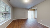 Located at 320 Hidden Valley Dr in Creedmoor, NC, this two-story home offers a functional and well-organized layout across both levels. The main floor welcomes you with rich hardwood-style flooring that extends throughout the living areas, neutral gray walls, and a textured ceiling. A large window and sliding glass door flood the living room with natural light and provide views of the surrounding greenery, while vertical blinds offer adjustable privacy. The entry features a staircase leading to the upper level, accompanied by a front door with a sidelight window.

The galley-style kitchen is well-appointed with warm wood cabinetry lining both sides, gray laminate countertops, a stainless steel sink, and black appliances including a range, dishwasher, and refrigerator. The kitchen flows toward the sliding glass door, creating a natural connection to the outdoor space.

Upstairs, the carpeted bedroom provides a comfortable retreat, featuring a window with natural views, ample wall space, and a closet. A full bathroom on this level includes a clean white tub-shower combination and standard fixtures. The upper level also reveals an open landing area and additional rooms, completing this practical and comfortable two-story home.