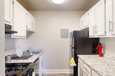 Located at 5521 Marlboro Pike in Capitol Heights, MD, this one-bedroom, one-bathroom unit offers a well-planned layout designed to maximize every square foot. The combined living and dining area serves as the heart of the home, featuring plush carpeting, neutral-toned walls, and a large window that invites natural light and outdoor views. The dining nook, illuminated by an overhead light fixture, provides a defined space for everyday meals. The galley-style kitchen is efficiently arranged with crisp white cabinetry, granite-look countertops, hardwood-style flooring, a gas range, and a black refrigerator — offering ample storage and workspace in a compact footprint. The bedroom is comfortably sized, continuing the soft carpet underfoot, and includes a closet with bi-fold doors for organized storage. A second closet adds additional storage convenience. The bathroom features hardwood-style flooring, a shower/tub combo, and a clean white vanity. Neutral tones and consistent finishes throughout the unit create a cohesive and move-in ready aesthetic. Two closets further enhance the unit's practical storage capacity, making this an efficient and comfortable residence.