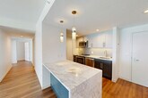 This well-appointed two-bedroom, two-bathroom residence in Cambridge, MA offers a thoughtfully designed single-level layout with a clean, modern aesthetic. The open-concept living and dining area is anchored by warm hardwood flooring and a large window that draws in natural light, creating a bright and welcoming atmosphere. The kitchen is a standout feature, boasting a substantial marble-topped island with pendant lighting overhead, dark shaker-style cabinetry, white upper cabinets, a subway tile backsplash, and a full suite of stainless steel appliances including a refrigerator, range, microwave, and dishwasher. The primary bedroom is generously sized, featuring hardwood floors and a large window with outdoor views. The second bedroom is carpeted and also benefits from ample natural light through its own window. Both bathrooms are finished in a clean, contemporary style, with one including a full tub-shower combination. Additional conveniences include in-unit laundry and four closets distributed throughout the home for plentiful storage. The overall design is modern and cohesive, with crisp white walls and consistent finishes tying each room together seamlessly.