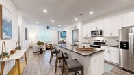 Located at 1775 Ashlar Dr in Fort Collins, CO, this well-appointed two-bedroom, two-bathroom residence offers a thoughtfully designed single-floor layout with modern finishes throughout. The open-concept kitchen and living area serves as the heart of the home, where crisp white shaker cabinets, a subway tile backsplash, dark quartz countertops, and a full suite of stainless steel appliances — including a French door refrigerator, electric range, and built-in microwave — create a polished, functional space. A peninsula with bar seating provides both additional prep space and a casual dining option. Wood-look luxury vinyl plank flooring extends through the main living areas, complementing the clean, contemporary aesthetic. The living room is bright and inviting, with large windows allowing generous natural light and a ceiling fan overhead. The primary bedroom features plush carpeting, a ceiling fan, a walk-in closet with built-in shelving and hanging rods, and an en-suite bathroom complete with a walk-in shower, white cabinetry, and quartz countertops. The second bedroom is equally well-sized and comfortable, served by a second full bathroom featuring a shower-tub combination. Recessed lighting throughout and a neutral color palette give the entire space a clean, modern ambiance.