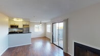 This single-floor residence offers a thoughtfully designed open-concept layout that seamlessly connects the living, dining, and kitchen areas. Rich, dark hardwood flooring flows throughout the main living spaces, creating a warm and cohesive aesthetic. The living room is anchored by a sleek fireplace and receives generous natural light through a large window and sliding glass door that opens to a private balcony, offering pleasant outdoor views.

The kitchen features white cabinetry, dark granite-style countertops, and stainless steel appliances including a gas range, over-the-range microwave, and refrigerator. A peninsula with a built-in sink provides additional prep space and a casual breakfast bar that bridges the kitchen and living area.

The bedrooms are comfortably sized, each with hardwood flooring, natural light from windows fitted with blinds, and sliding closet doors offering practical storage. A built-in shelving nook adds functional storage space near the entry area.

The two full bathrooms are finished consistently, each featuring a tub/shower combination with a curved curtain rod, dark granite-style vanity countertops, and brushed nickel fixtures and hardware. The overall palette of neutral walls and warm wood tones creates a clean, inviting atmosphere throughout the space.