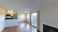 This single-floor residence offers a thoughtfully designed open-concept layout that seamlessly connects the living, dining, and kitchen areas. Rich, dark hardwood flooring flows throughout the main living spaces, creating a warm and cohesive aesthetic. The living room is anchored by a sleek fireplace and receives generous natural light through a large window and sliding glass door that opens to a private balcony, offering pleasant outdoor views.

The kitchen features white cabinetry, dark granite-style countertops, and stainless steel appliances including a gas range, over-the-range microwave, and refrigerator. A peninsula with a built-in sink provides additional prep space and a casual breakfast bar that bridges the kitchen and living area.

The bedrooms are comfortably sized, each with hardwood flooring, natural light from windows fitted with blinds, and sliding closet doors offering practical storage. A built-in shelving nook adds functional storage space near the entry area.

The two full bathrooms are finished consistently, each featuring a tub/shower combination with a curved curtain rod, dark granite-style vanity countertops, and brushed nickel fixtures and hardware. The overall palette of neutral walls and warm wood tones creates a clean, inviting atmosphere throughout the space.