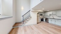 Located at 160 Seabury St in Fall River, MA, this two-bedroom, two-bathroom residence spans two floors, offering a well-organized layout with a larger main level and a slightly more compact upper floor. The main level features light hardwood flooring throughout, an open living area, and a kitchen equipped with stainless steel appliances, white cabinetry, and a classic subway tile backsplash. A striking staircase with a black iron railing connects both floors and serves as a visual focal point, complemented by soaring wall height that enhances the sense of openness.

The upper floor includes a hallway that leads to both bedrooms, each featuring hardwood flooring and closet space with built-in rods and shelving. The primary bedroom offers a comfortable footprint with natural light from a window. Both bathrooms are finished with hexagonal tile flooring, granite-topped vanities with undermount sinks, and framed mirrors. One bathroom features a glass-enclosed walk-in shower, while the other provides additional flexibility. The overall aesthetic throughout is clean and contemporary, with neutral tones, recessed lighting, and wall sconces contributing to a bright, modern ambiance.