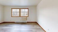 Located at 1110 S Wells St in Lake Geneva, Wisconsin, this 2-bedroom, 1-bathroom unit offers a functional and well-appointed single-floor layout. The open-concept kitchen and living area serves as the heart of the home, featuring light wood-style flooring throughout, warm wood trim accents, and a ceiling fan that adds comfort and airflow. The kitchen is well-equipped with stainless steel appliances including an electric range and full-size refrigerator, complemented by white cabinetry with wood trim detailing, a butcher block-style countertop, a built-in range hood, and a corner sink with pendant lighting above. The living room benefits from natural light through dual windows with wood-framed trim and includes a baseboard heating unit. The primary bedroom offers generous closet space with two sets of bifold doors and direct access to a private deck through a sliding glass door, bringing in additional natural light and outdoor views. The second bedroom features soft carpeting and warm-toned wood doors. The bathroom includes a full tub and shower combination in a clean, white finish. The overall aesthetic is clean, simple, and move-in ready, ideal for those seeking comfortable living near the amenities of Lake Geneva.