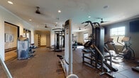 Located in the Rancho Peñasquitos neighborhood of San Diego, this single-floor fitness center at 10977 Pacific Point Place offers a comprehensive workout facility designed to accommodate a wide range of exercise needs. The space is organized into distinct functional zones, each thoughtfully appointed with professional-grade equipment.

The cardio area is well-lit by multiple windows that allow generous natural light to fill the room, and features a row of treadmills, elliptical trainers, stationary bikes, and step machines positioned beneath ceiling fans and wall-mounted televisions for an engaging workout experience. Adjacent to this zone, a dedicated strength training area houses a variety of cable machines and selectorized equipment, providing options for both upper and lower body training.

A separate free weights and functional training room offers a power rack, adjustable benches, and stability balls, bathed in natural light streaming through surrounding windows. Large floor-to-ceiling mirrors along one wall visually expand the space and support proper form during exercise. Throughout the facility, durable rubber flooring provides safety and noise reduction.

The entrance area features double glass doors, open shelving for towels and personal items, and easy access to all sections of the gym. Crown molding and recessed lighting lend a polished, well-maintained aesthetic throughout the facility.