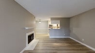 This efficiently designed single-story residence offers a thoughtful layout across one bedroom, one bathroom, a living room, kitchen, hallway, and closet. Light-toned luxury vinyl plank flooring runs consistently throughout the space, lending a clean, cohesive aesthetic to every room.

The living room serves as the centerpiece of the home, highlighted by a marble-surround fireplace with a crisp white mantel. A sliding glass door with vertical blinds fills the room with natural light and provides outdoor access. A ceiling fan adds both function and character overhead, while a textured popcorn ceiling adds a classic touch.

The kitchen is configured as a galley-style layout with white cabinetry, light stone countertops, and stainless steel appliances including a range, microwave, and refrigerator. A peninsula with a built-in sink opens toward the living area, offering a convenient pass-through feel.

The bedroom is a comfortable, well-proportioned room featuring a window with blinds that allows natural light in and views of the outdoors. The bathroom is clean and functional, equipped with a white vanity, a well-lit mirror, and matching white cabinetry. The neutral gray wall palette throughout the unit creates a calm, modern ambiance well-suited for everyday living.