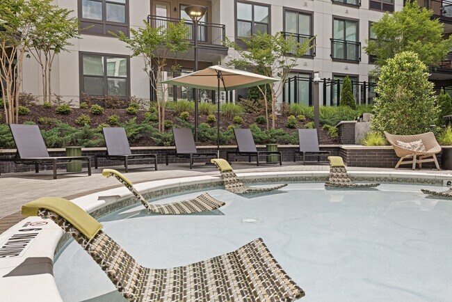 Piscina estilo resort con zona para tomar el sol, cabañas y terraza. - Bexley Chamblee