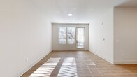 Located at 346 W 26th St in Charlotte, NC, this single-floor, two-bedroom, two-bathroom residence offers a clean, modern aesthetic throughout. The open-concept living area is finished with light-toned hardwood-style flooring and crisp white walls, with large windows and a glass-paneled exterior door that flood the space with abundant natural light. The living area flows seamlessly into the kitchen, which features gray shaker-style cabinetry with matte black hardware, granite-look countertops, a classic white subway tile backsplash, and black stainless steel appliances including a range, microwave, and refrigerator. A kitchen island provides additional prep and counter space.

Both bedrooms are carpeted and receive generous natural light through large windows with views of the surrounding neighborhood. Ceiling fans are installed in each bedroom for added comfort. The two bathrooms are finished consistently with light wood-look flooring, white subway tile tub surrounds, granite-topped vanities with gray cabinetry, and brushed nickel fixtures. The overall design palette—neutral tones, modern hardware, and consistent finishes—creates a cohesive and contemporary living environment throughout.
