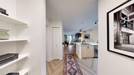 Located in Seattle's Queen Anne neighborhood, this thoughtfully designed one-bedroom, one-bathroom residence offers a cohesive blend of modern finishes and warm, curated design. Herringbone-patterned hardwood floors run throughout the unit, creating a distinctive and elegant foundation for the open-concept layout.

The kitchen is well-appointed with white upper cabinetry, light wood lower cabinets, a white quartz countertop, stainless steel appliances, a dark geometric tile backsplash, and track lighting overhead. It flows seamlessly into the combined living and dining area, making the space feel open and connected.

The living room is a standout, featuring arched sage-green accent panels flanking framed artwork, black wall sconces, and a sliding glass door that opens to a private balcony with tree-lined views — filling the room with natural light.

The bedroom continues the refined aesthetic with a bold two-tone sage and gray accent wall, herringbone flooring, and its own sliding glass door leading to a balcony overlooking lush greenery.

The bathroom features light wood cabinetry, a white quartz vanity top, and an arched mirror with black hardware, maintaining the unit's consistent modern style. A hallway with a closet connects the spaces efficiently, completing this well-appointed Seattle residence.