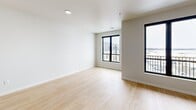 This contemporary apartment offers a thoughtfully designed living space of 1360 square feet on a single floor. The layout includes three bedrooms, with the primary bedroom boasting a generous 190 square feet. The open-concept design seamlessly integrates the kitchen and living room, creating a spacious and fluid environment.

The kitchen is a standout feature, showcasing dark gray cabinetry, stainless steel appliances, and a large central island with a light-colored countertop. Pendant lighting adds a modern touch, while the light wood flooring throughout maintains a bright, airy feel.

Large windows in the bedrooms and living areas flood the space with natural light and provide scenic views of the surrounding area. Some rooms feature carpeting, adding warmth and comfort.

The bathroom is equipped with a modern walk-in shower, featuring clean lines and a minimalist design. Throughout the apartment, the color palette is predominantly neutral, with white walls creating a blank canvas for personalization.

The apartment's design prioritizes functionality without sacrificing style, making efficient use of the available space. With its blend of contemporary finishes and practical layout, this apartment offers a comfortable and stylish urban living experience.
