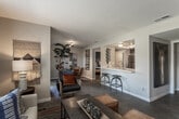 Located at 1809 Baywood Dr in Corona, California, this single-story home offers a well-organized layout with a cohesive contemporary design aesthetic. The living room serves as the heart of the home, featuring wood-style flooring, large windows with blinds and drape panels that invite abundant natural light, and a warm, layered color palette accented by earthy tones and bold textiles. The space flows naturally into a dining area positioned adjacent to a sliding glass door, which provides direct access to an outdoor area and further enhances the sense of openness.

The kitchen is equipped with stainless steel appliances, including a gas range, over-the-range microwave, and full-size refrigerator. Rich, dark cabinetry pairs with light countertops and a subway tile backsplash to create a functional yet visually appealing workspace.

The home includes multiple bedrooms, each featuring wood-style flooring, natural light from exterior-facing windows, and ample closet space. One bedroom offers a built-in vanity area with dark cabinetry and a well-lit mirror alongside sliding closet doors. The bathrooms are clean and functional, each outfitted with a tub-shower combination, vanity with storage, and wood-look tile flooring. Overall, the home presents a modern and inviting atmosphere throughout.