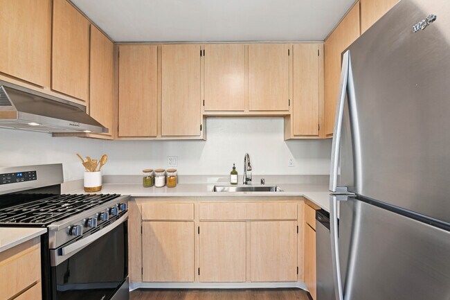 Cocina Classic Package II con electrodomésticos de acero inoxidable, gabinetes de roble, encimeras de cuarzo beige y pisos de superficie dura. - eaves Mission Ridge