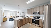 Located at 1880 Maple Dr NW in Kennesaw, Georgia, this thoughtfully designed one-bedroom, one-bathroom residence offers a comfortable and modern living experience across a single floor. The open-concept layout seamlessly connects the kitchen and living room, creating a spacious and airy atmosphere throughout.

The kitchen is a standout feature, showcasing wood-grain cabinetry, a white quartz peninsula with bar seating, a classic subway tile backsplash, and a full suite of stainless steel appliances including a refrigerator, range, microwave, and dishwasher. Pendant lighting above the peninsula adds a stylish, modern touch.

The living room is bright and welcoming, with large windows dressed in sheer curtains that invite abundant natural light. Light hardwood-style flooring runs throughout the main living areas, complementing the neutral color palette.

The bedroom is a serene retreat, featuring plush carpet, a ceiling fan, and a generous window with outdoor views. A dedicated closet provides practical storage. The bathroom is clean and classic, with a subway-tiled tub-shower combination, wood-look flooring, and refined brushed nickel fixtures throughout. The overall ambiance is modern, warm, and inviting.
